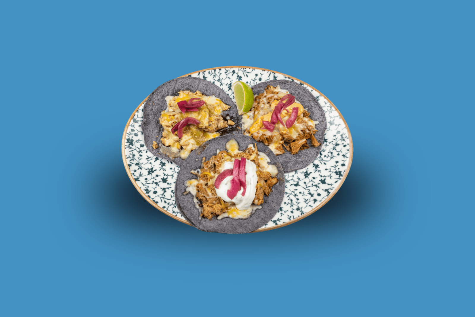 Drei Tacos mit Käse, Sauce und eingelegten Zwiebeln