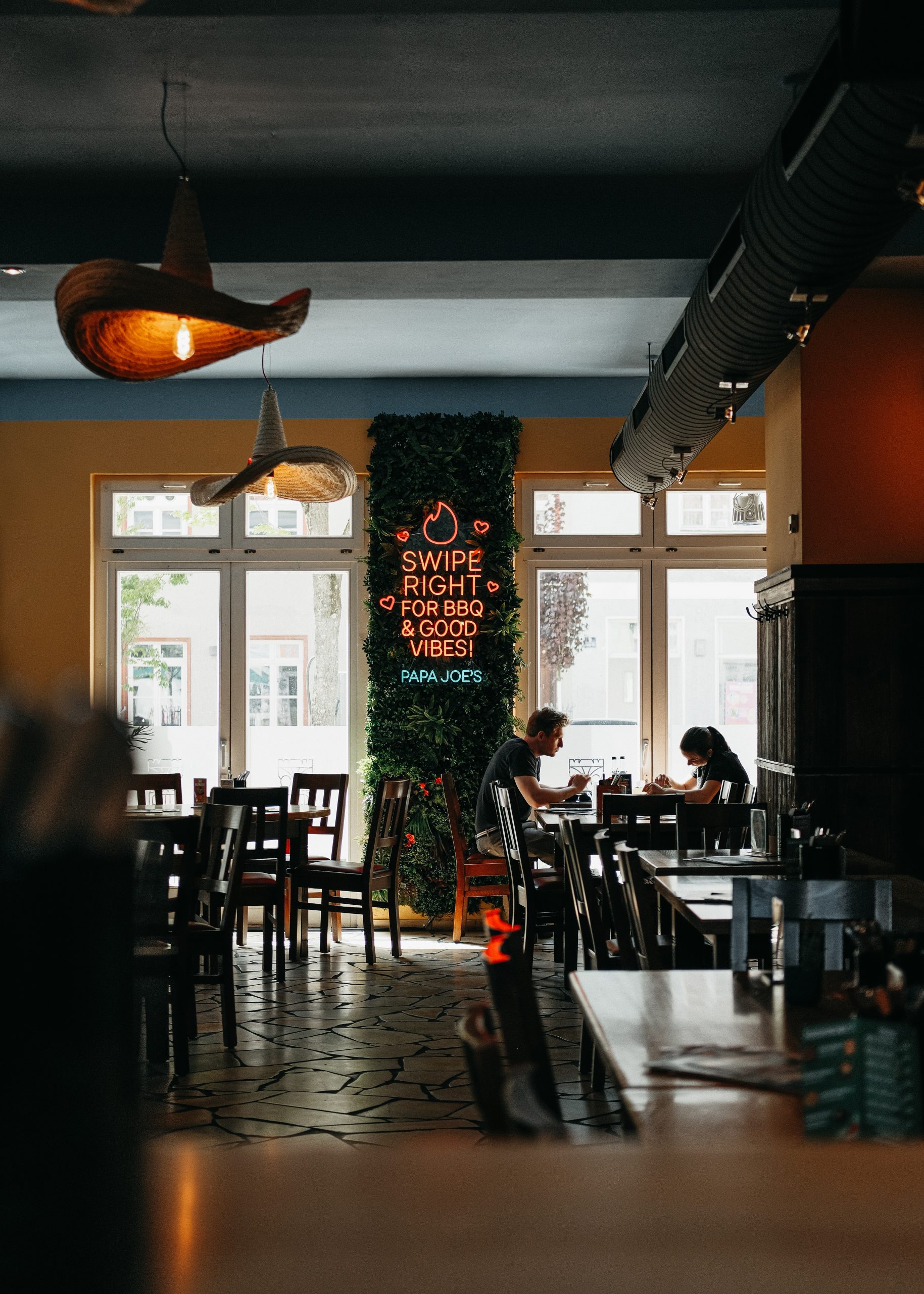 Restaurantbereich des Papa Joe’s mit Blick auf den Neon-Schriftzug